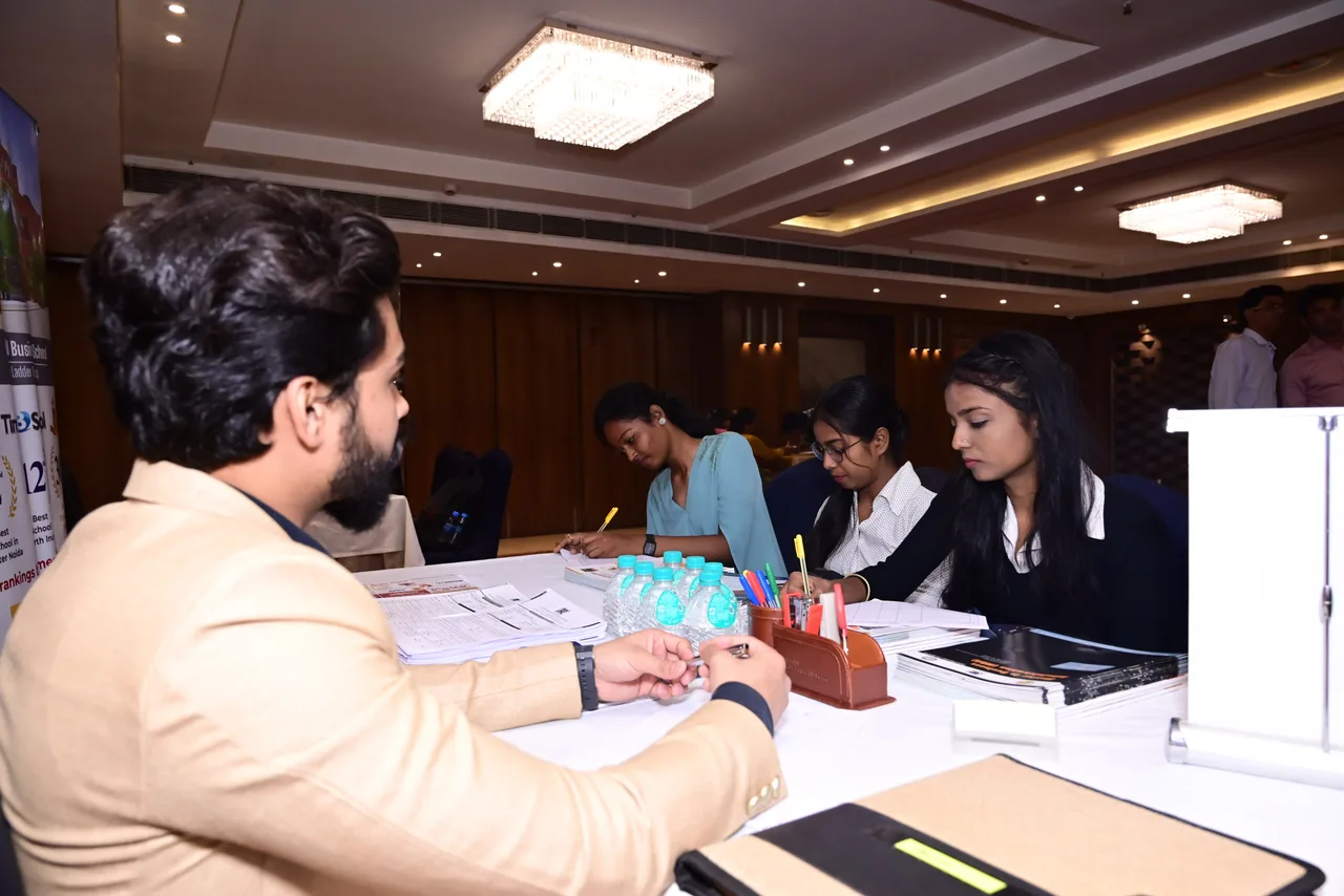 An education representative at a desk with students reviewing materials